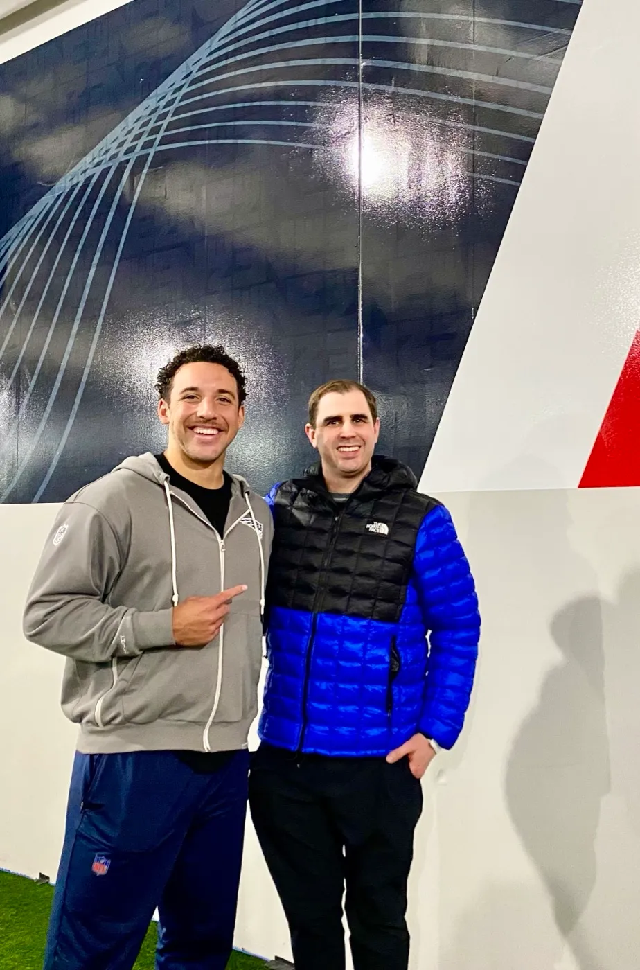 Nathan Brennan standing with NFL long snapper Julian Ashby at an indoor training facility